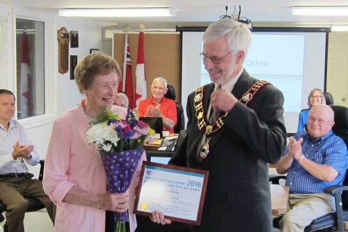 Eileen Flieler was presented with the Senior Of The Year Award by Mayor Ron Higgins to a full house of family and friends at the June 30 council meeting in Plevna.